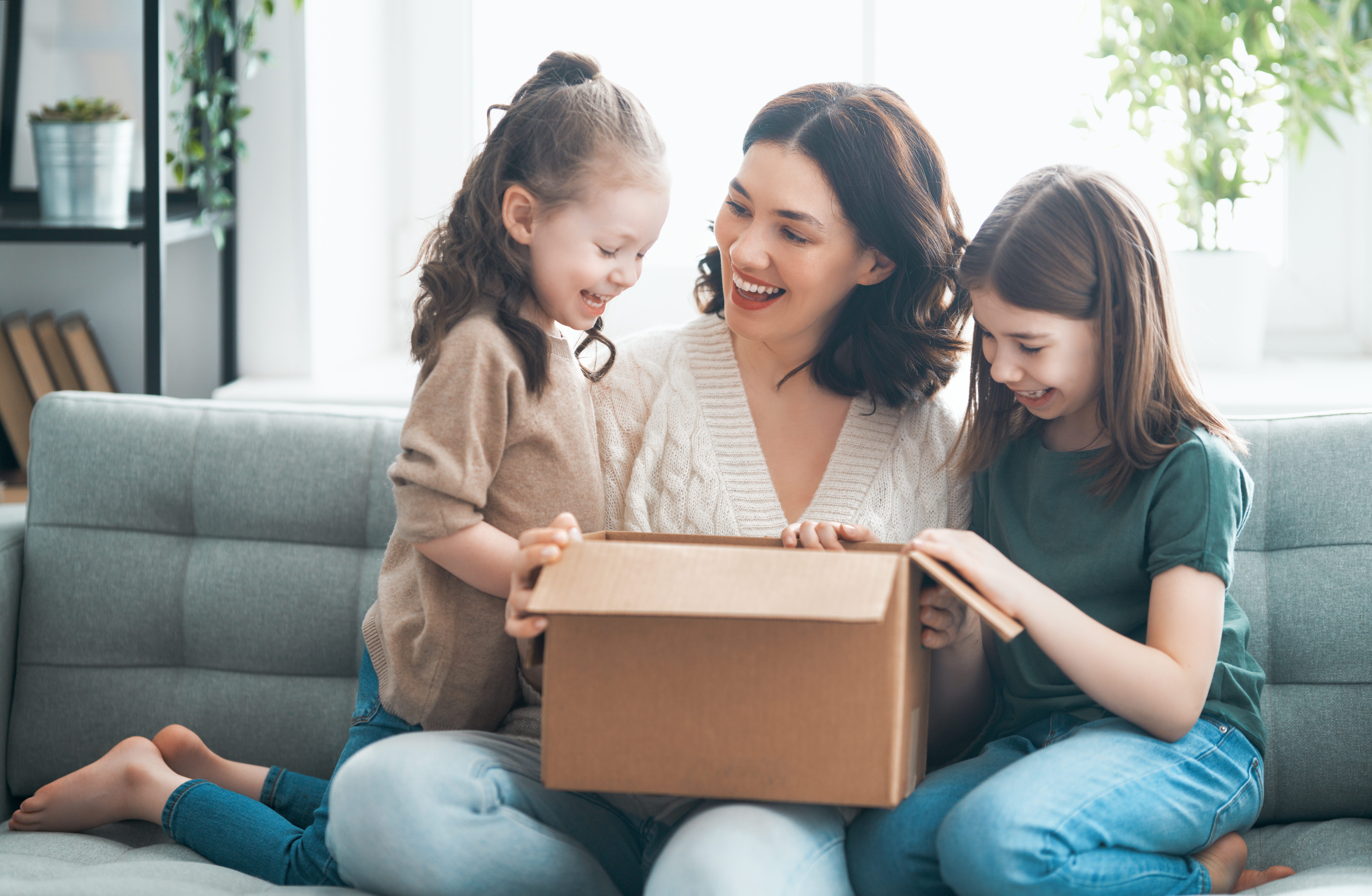 Mujer y dos niñas abriendo una caja